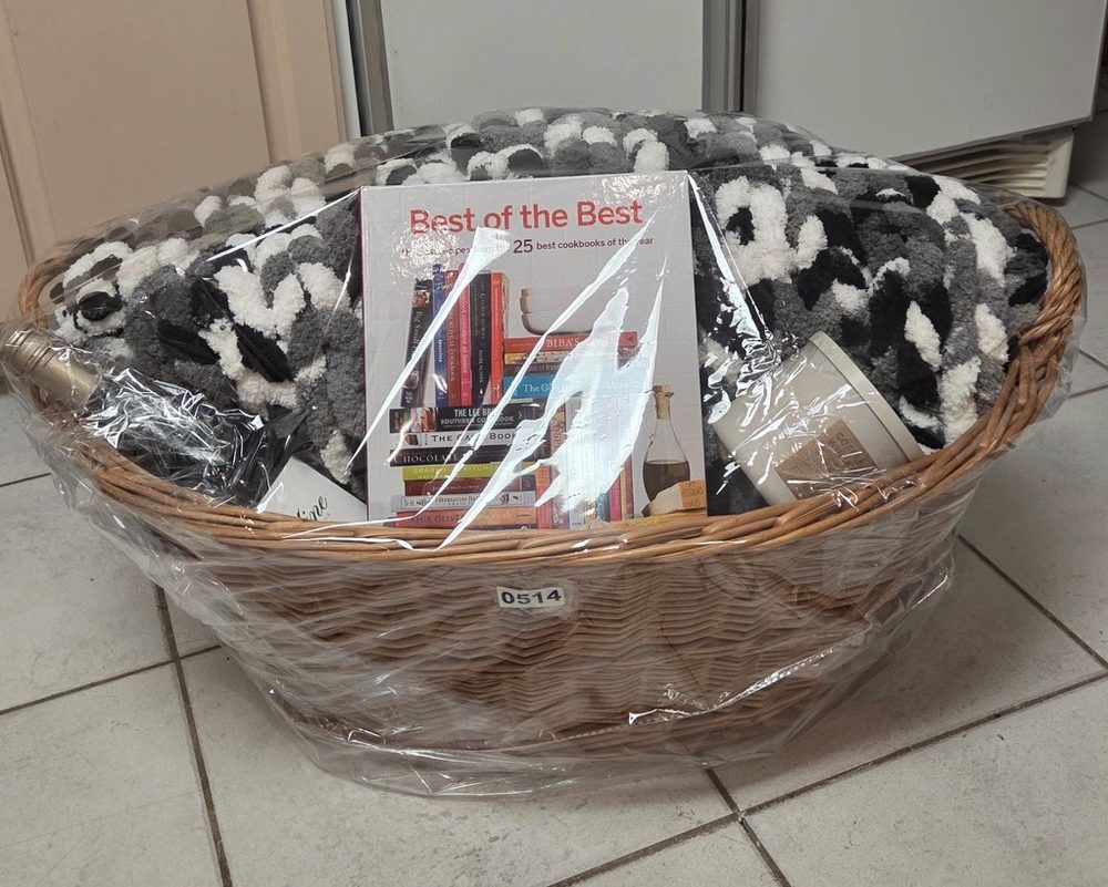 Wicker basket with a chunky gray and white blanket and a cookbook
